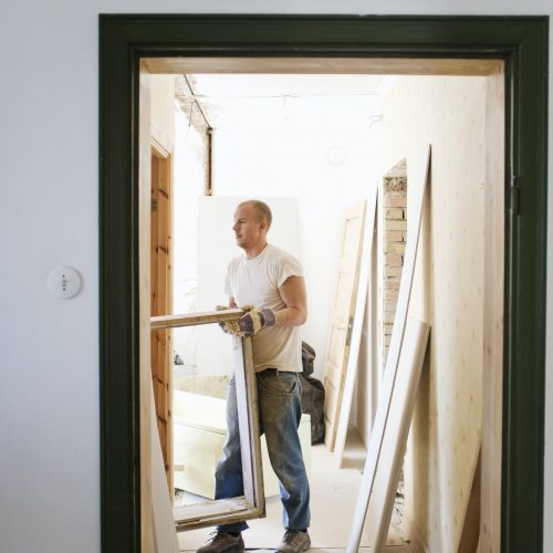 Carpentry carrying window frame seen through doorway in room